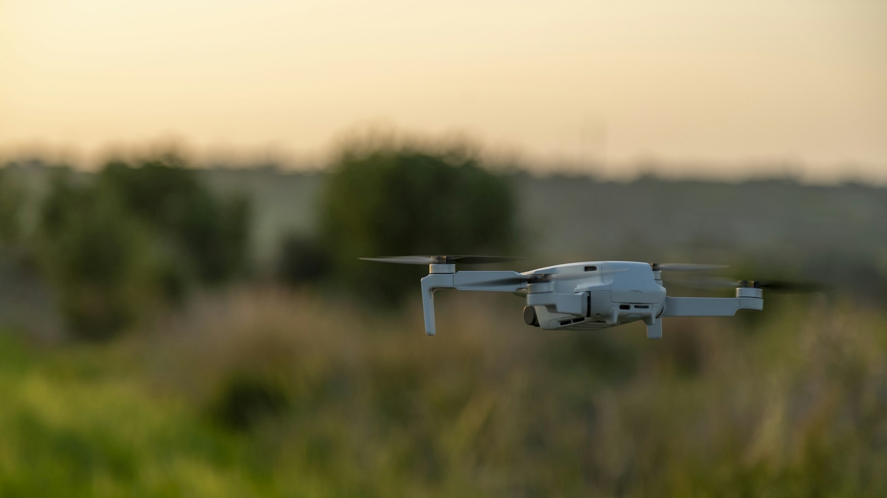 Drone flying over a green field at sunset